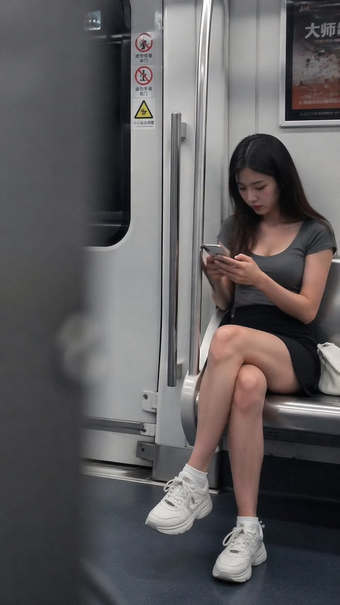 Inside the subway carriage, a young woman sits on a seat near the…